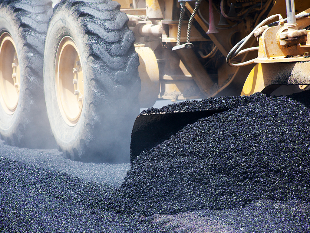 industrial pavement truck laying fresh asphalt on construction site